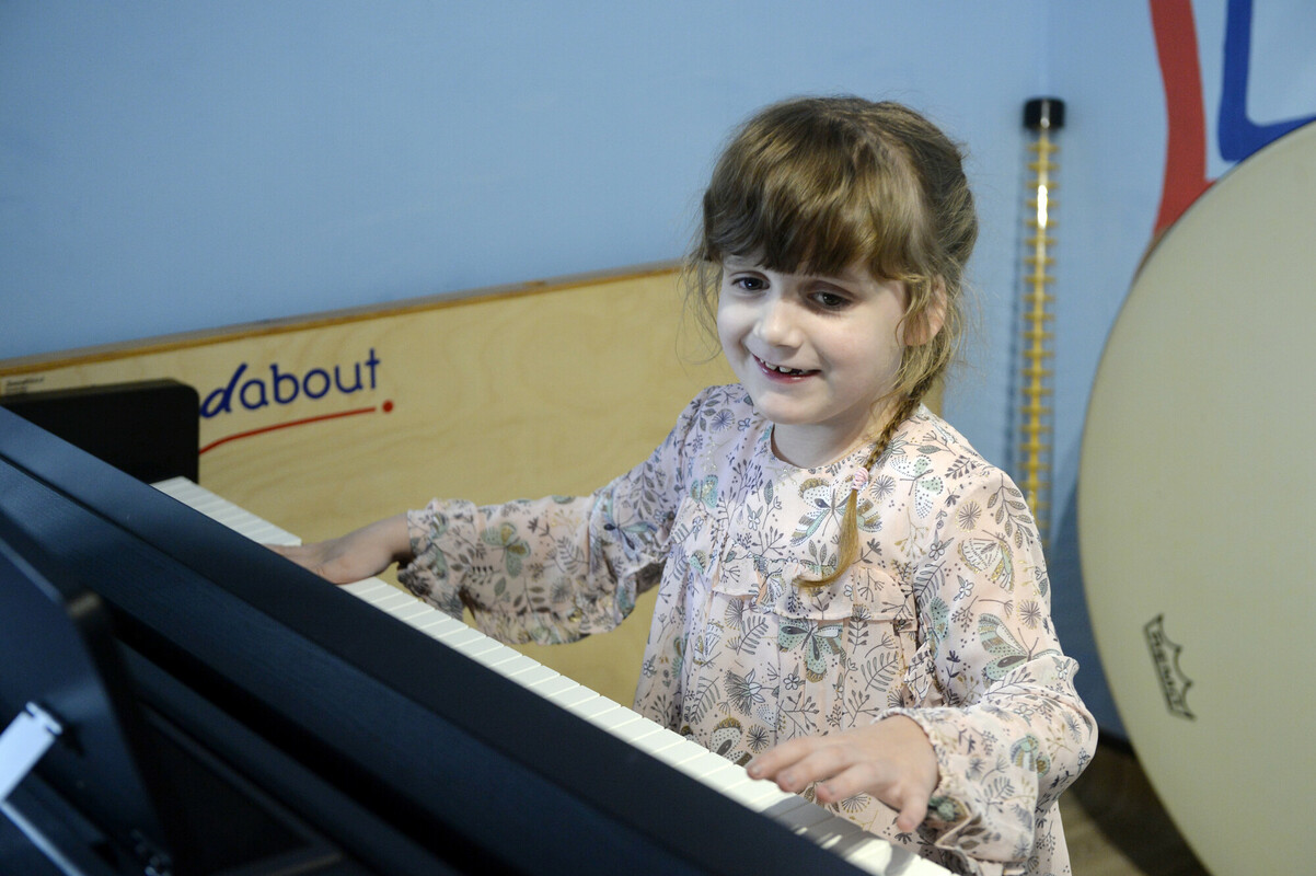 Hallie playing the keyboard in the music room.