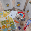 A range of different Easter themed items including bags with a baby chick on, a blanket, a sheep plush toy and a small pouch