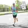 A man in a Demelza vest running along a road