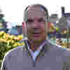 Chair of Investment Committee Paul Hewish stands in sunny gardens, wearing a beige zip top jumper.