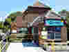 Entrance to Demelza East Sussex Community Hub with bright signage and accessible pathway, inviting visitors in.