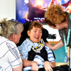 A young male teenager smiling while his mum and Transition Navigator Claire look at him also smiling