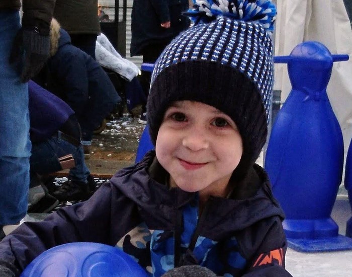 Zak enjoying ice skating, wearing a blue bobble hat.