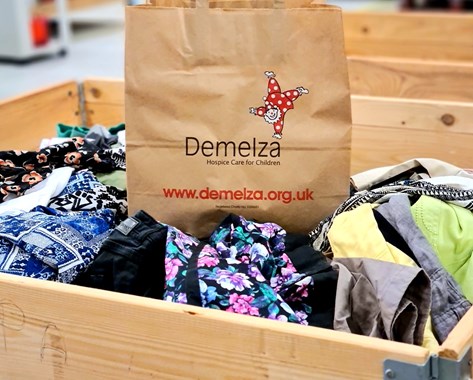A brown paper bag with the Demelza logo.