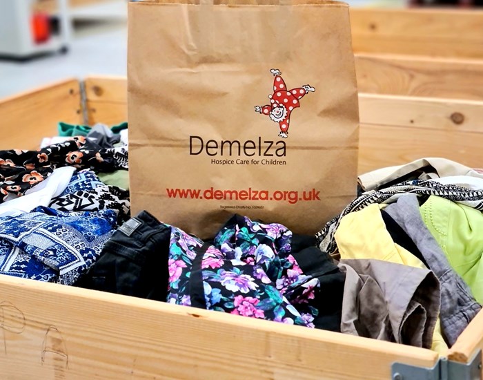 A brown paper bag with the Demelza logo.