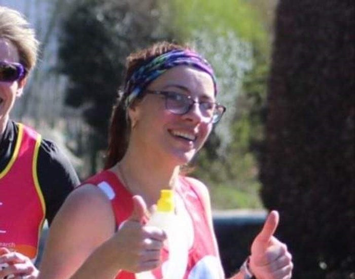 Lyn is running in her dotty Demelza vest, with her thumbs up.