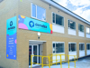 Two-story brick building with 'Demelza' sign and colorful graphics. Side panel promotes ways to support. Yellow railings lead to entrance.