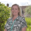 Katie Stevens, Director of Clinical Services, stands in Demelza’s gardens wearing a patterned top and smiling.