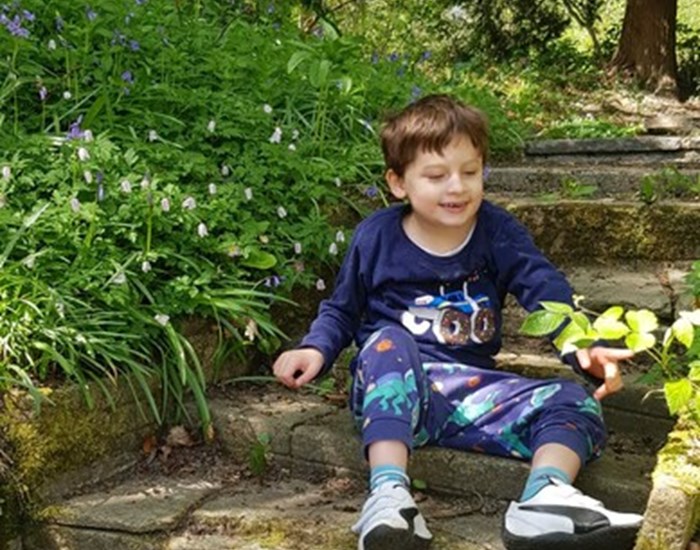 Oakley sits on the steps in his garden, wearing little wellington boots.