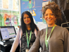 Two ladies smiling to camera behind the till in a charity shop