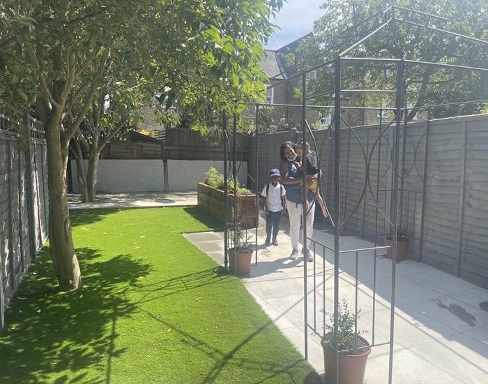 A post-makeover garden, with freshly laid grass, new paving and painted fences.