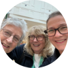 Three women with Demelza lanyards on smiling towards the camera