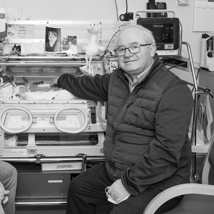 Jade's uncle and grandfather sit next to her as she lays in an incubator.