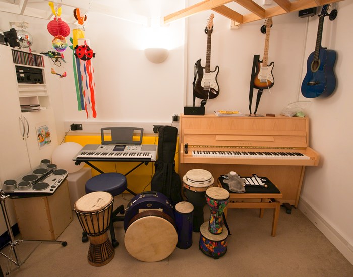 A room filled with guitars, drums, a piano and a keyboard.