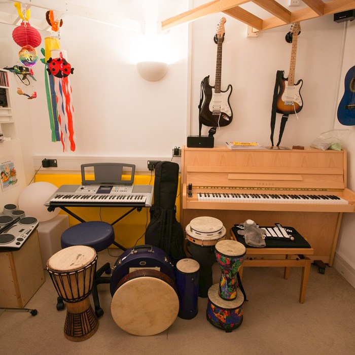 A room filled with guitars, drums, a piano and a keyboard.