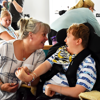 A mum looking at her son in a wheelchair holding his hand while smiling