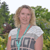 Charlotte Chamberlain, Director of Finance and Resources, stands smiling in Demelza’s hospice gardens wearing a patterned top.