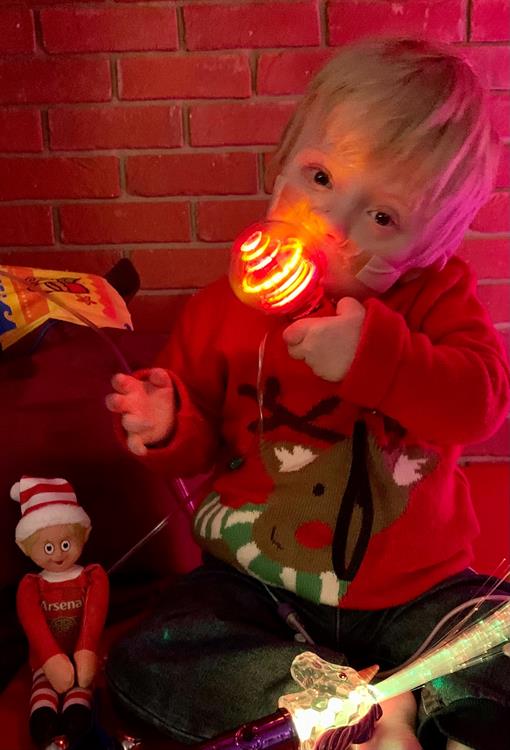 Dennie is wearing a reindeer jumper, playing with a glow stick.