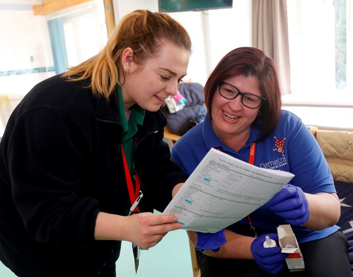 A Demelza nurse and health care assistant look at paperwork together.
