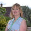 Claire Ellis-Waghorn, Director of IT, Data and Governance, stands in Demelza’s gardens wearing a blue floral dress