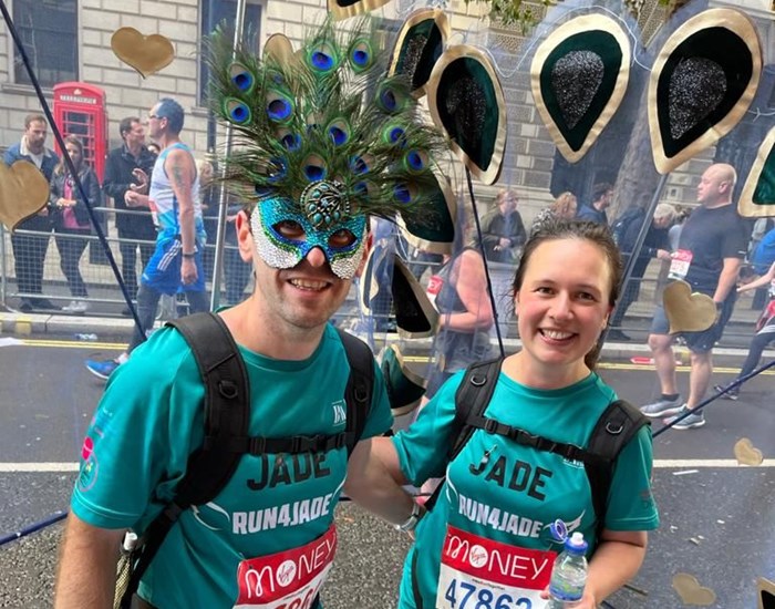 A man and woman, dresses as turquoise peacocks, running the London Marathon.