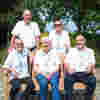 Five Demelza volunteers in the Garden of Tranquility sitting on a bench smiling