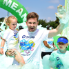 An image of an older man covered in green bubbles holding a young girl up to his shoulders