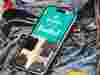 Smartphone showing 'demelza now on Vinted' with clothing images, placed on denim fabric background with colorful shapes.