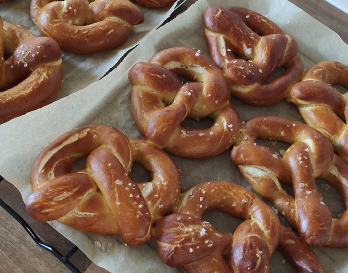Six large pretzels on a baking tray.