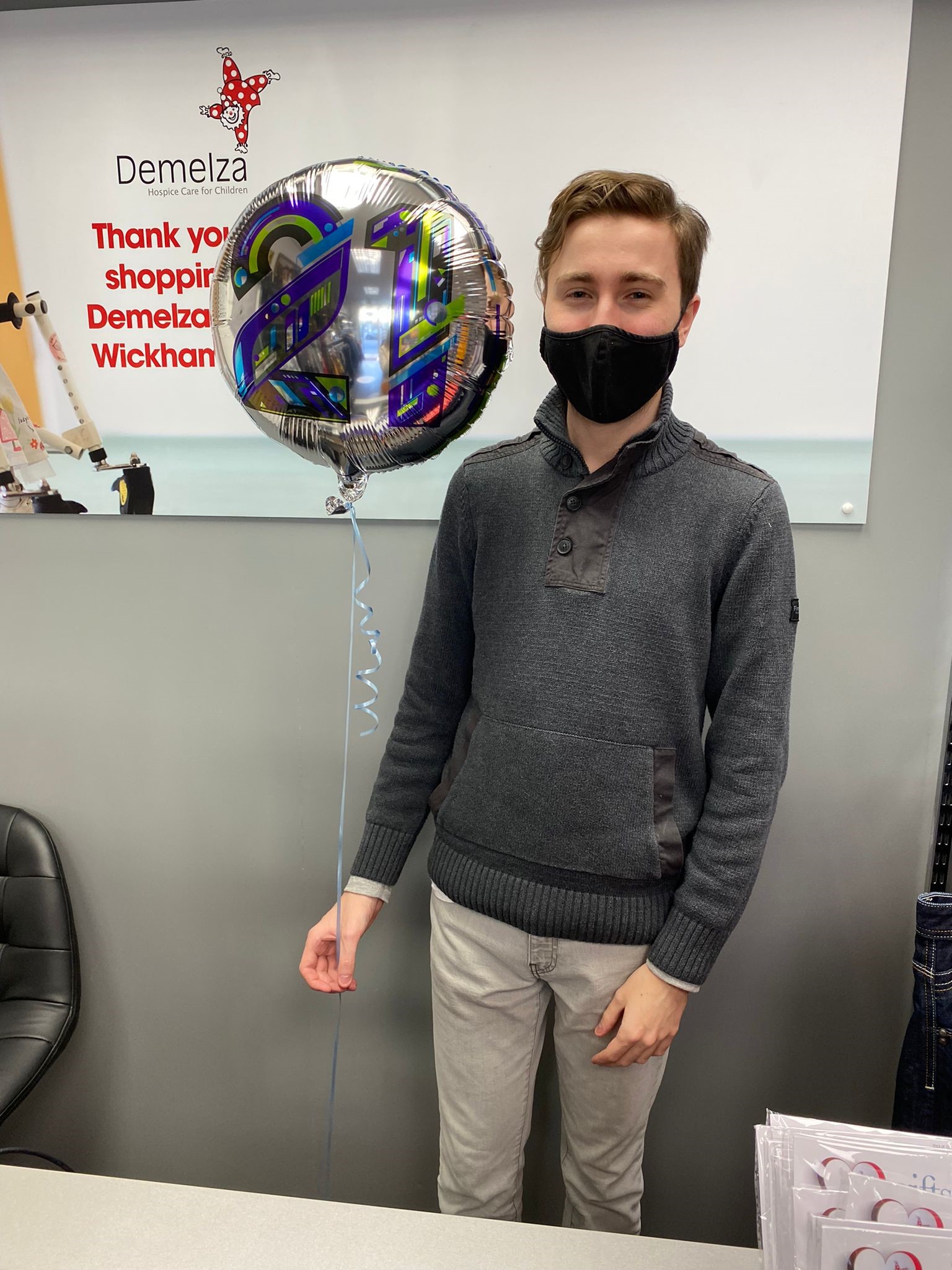 Assistant Manager Nathan, standing next to birthday balloon.