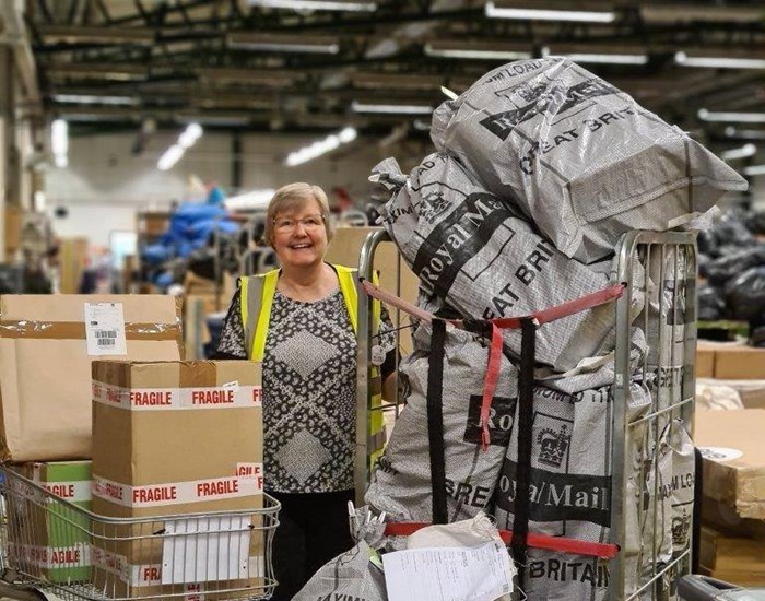 A volunteer wearing a hi-vis jacket is sorting through bags of donations.