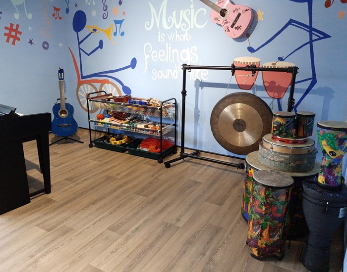 A room filled with a gong, a piano, drums and other music instruments.