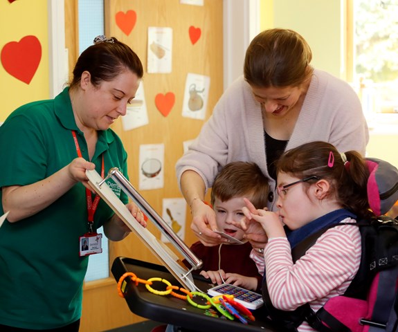 Chloe and her family play together, with a health care assistant.