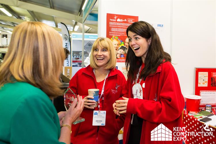 Two ladies wearing red Demelza fleeces, holding collection pots and a corporate event.