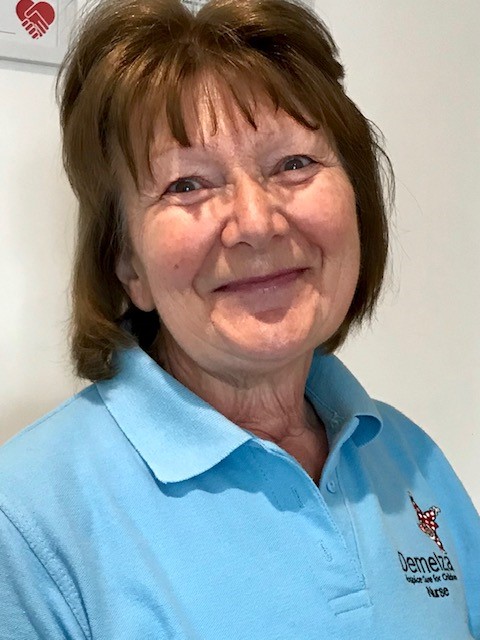 A Demelza nurse wearing a light blue polo top, smiling.