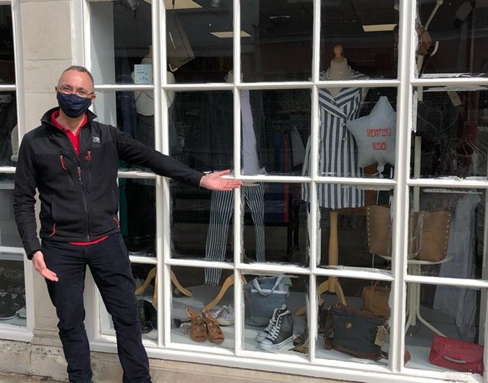 Former CEO Ryan Campbell standing outside a Demelza charity shop window, wearing a black face mask.