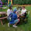 Mason, seated in his wheelchair, smiles as a PAT dog rests on his lap during Kent Family Fest 2025, surrounded by family outdoors.