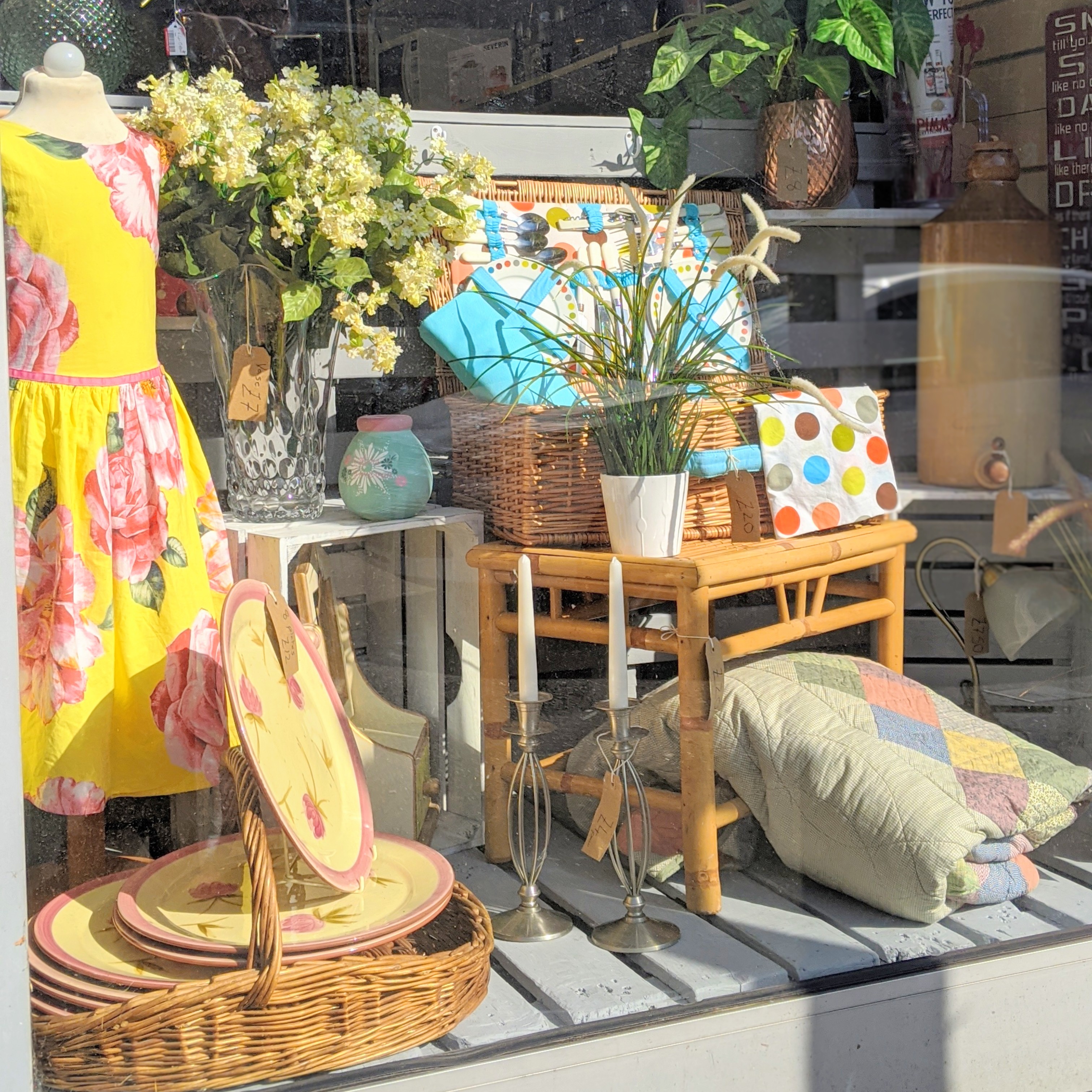A window display with a yellow dress and flowers.