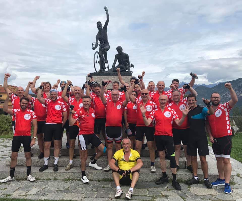 A group photo of Team Demelza cyclists, all wearing red cycling tops.