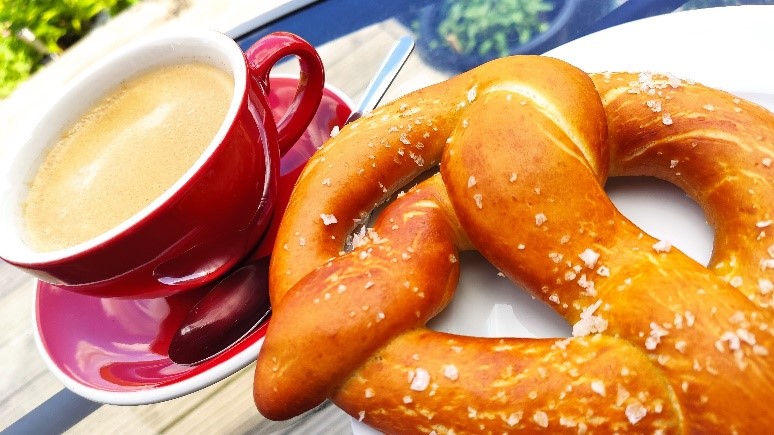 A large pretzel and a red mug filled with tea.