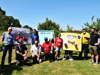 Royal Mail volunteers and two mascots stand together in a sunny garden at Demelza Kent.