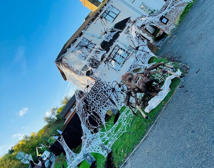 A house has been decorated for Halloween, with huge cobwebs and a giant spider.