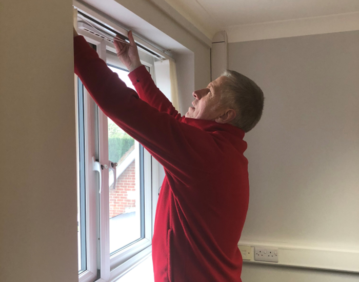A practical support volunteer puts up blinds.