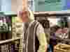 Volunteer Dave stands behind the till at the Tenterden shop, smiling warmly at customers.