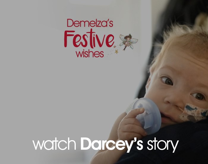 Baby Darcey rests on the shoulder of a Demelza nurse, holding a dummy to her mouth.