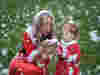 A woman and a child in Santa outfits looking at snow in the woman's hands