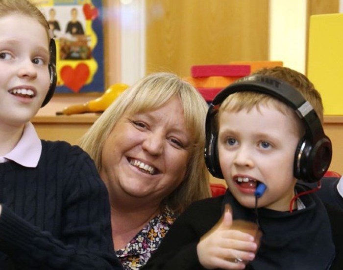 Two children wearing headphones, laughing with their parents.