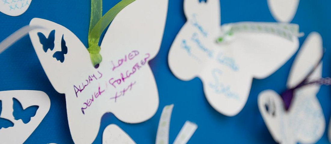 White cut out butterflies with remembrance messages written on them.