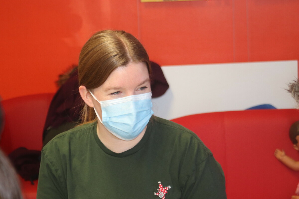 A Demelza Health Care Assistant, wearing a face mask and green Demelza t-shirt.