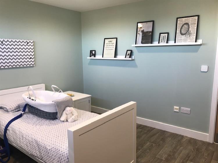 A bereavement suite at Demelza, with peaceful light blue walls, a single bed and a cold cot.